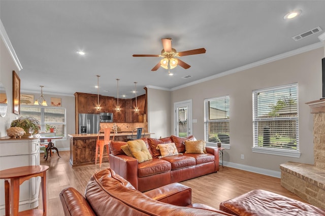 living area with baseboards, visible vents, a ceiling fan, and light wood-style floors
