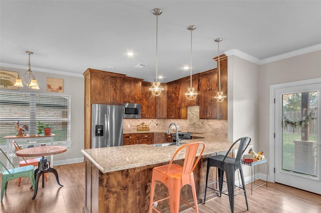 kitchen featuring light stone countertops, stainless steel appliances, decorative backsplash, light wood-style flooring, and a peninsula