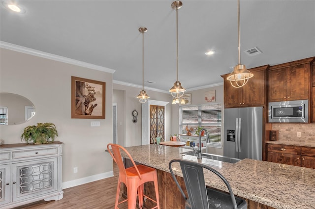 kitchen featuring appliances with stainless steel finishes, ornamental molding, a sink, baseboards, and visible vents