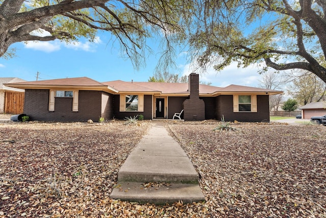 single story home featuring a chimney, brick siding, and fence