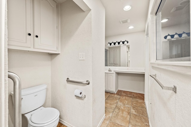 bathroom with baseboards, recessed lighting, toilet, vanity, and stone tile floors