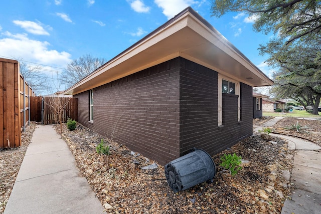 view of property exterior featuring brick siding and fence