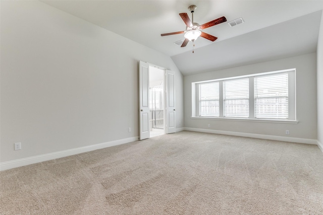 empty room with light carpet, a ceiling fan, baseboards, lofted ceiling, and visible vents