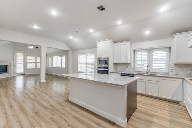 kitchen featuring decorative backsplash, a center island, a sink, a premium fireplace, and stainless steel appliances
