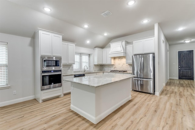 kitchen featuring custom exhaust hood, a kitchen island, white cabinets, backsplash, and stainless steel appliances
