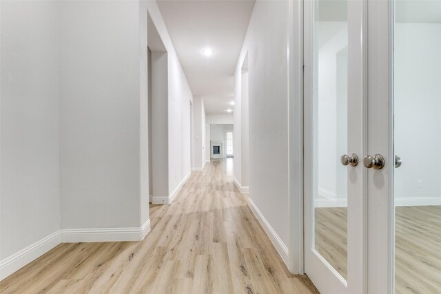 hall with light wood-style floors and baseboards