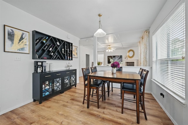 dining room featuring baseboards, ceiling fan, a bar, and wood finished floors