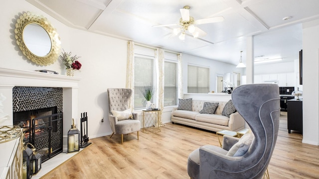 living area featuring baseboards, light wood-style floors, ceiling fan, and coffered ceiling