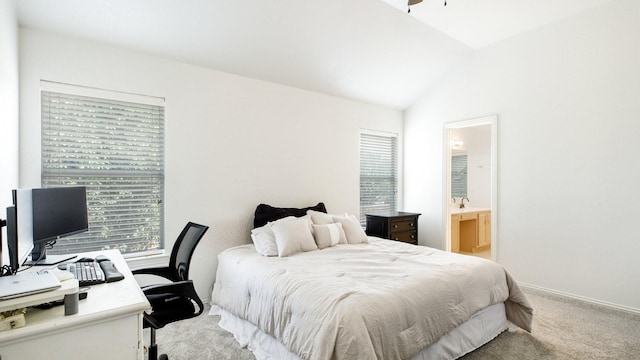 bedroom featuring vaulted ceiling, light carpet, multiple windows, and ensuite bath