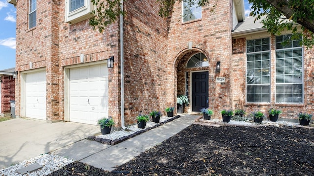 property entrance featuring brick siding, a garage, and concrete driveway