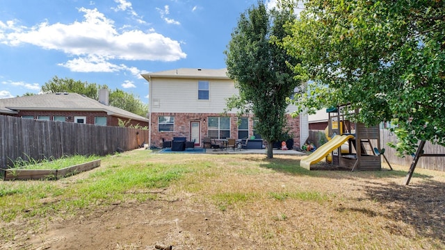 rear view of house with brick siding, a fenced backyard, a patio area, a playground, and a lawn