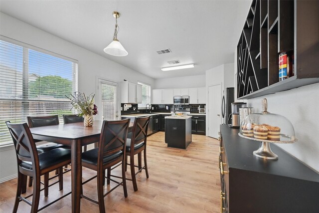kitchen with visible vents, appliances with stainless steel finishes, a center island, a sink, and white cabinets