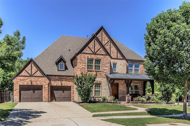 tudor-style house with fence, concrete driveway, a front lawn, and brick siding