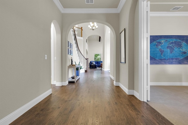 hallway with crown molding, arched walkways, dark wood-type flooring, and visible vents