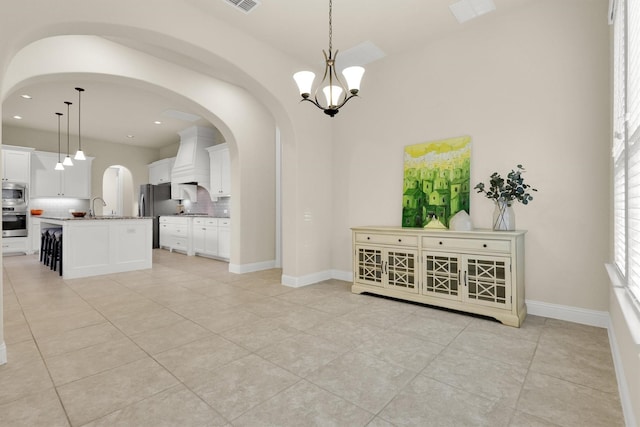dining space featuring baseboards, recessed lighting, a chandelier, arched walkways, and light tile patterned floors