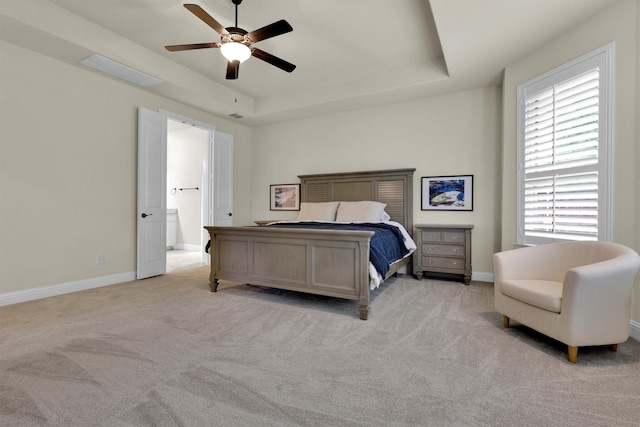 bedroom with a ceiling fan, baseboards, light carpet, and a tray ceiling