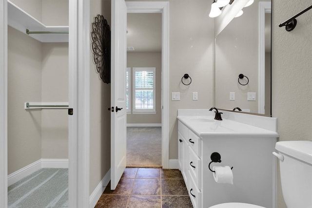 bathroom featuring vanity, baseboards, and toilet