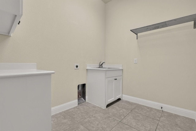 clothes washing area featuring a sink, baseboards, light tile patterned floors, and cabinet space