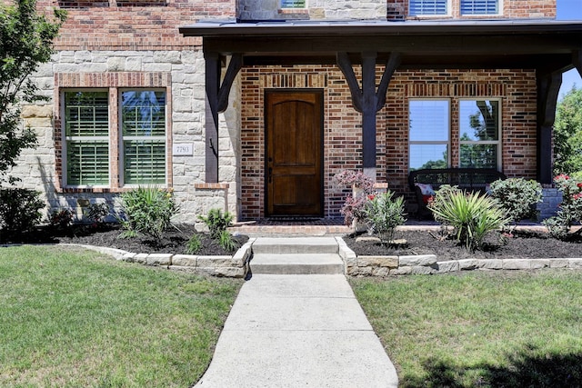 property entrance with a yard and brick siding