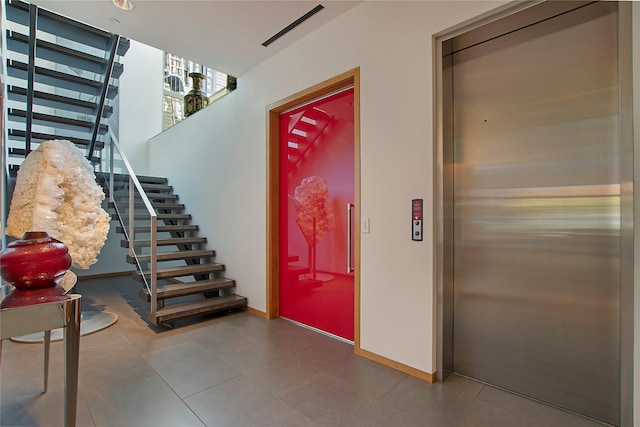 interior space with baseboards, visible vents, and elevator