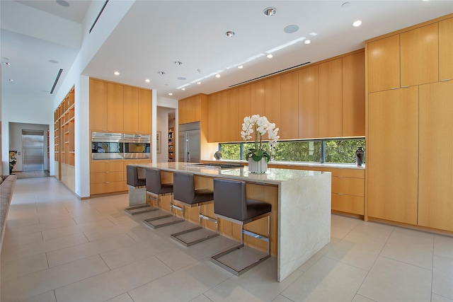 kitchen featuring plenty of natural light, light stone counters, appliances with stainless steel finishes, a center island, and modern cabinets