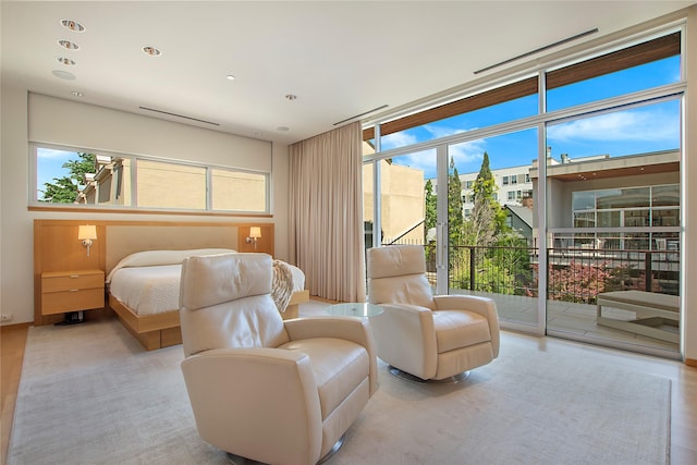 bedroom featuring access to exterior, wood finished floors, and expansive windows
