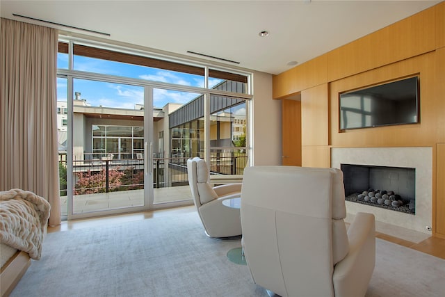 living area featuring floor to ceiling windows, wood finished floors, and a fireplace with flush hearth