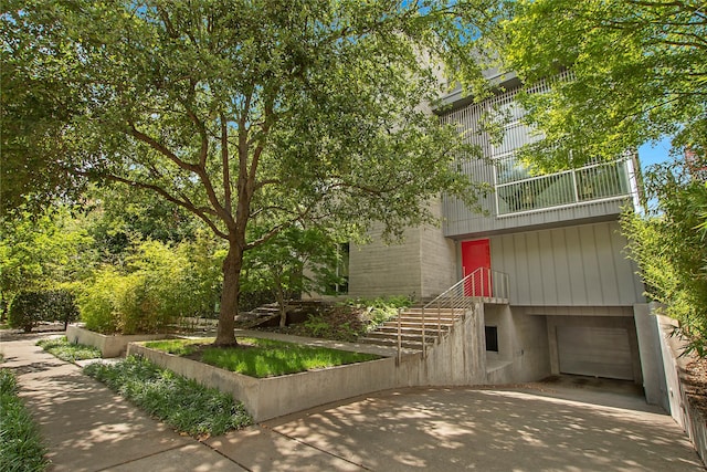 view of front of property featuring stairway, brick siding, a balcony, and an attached garage
