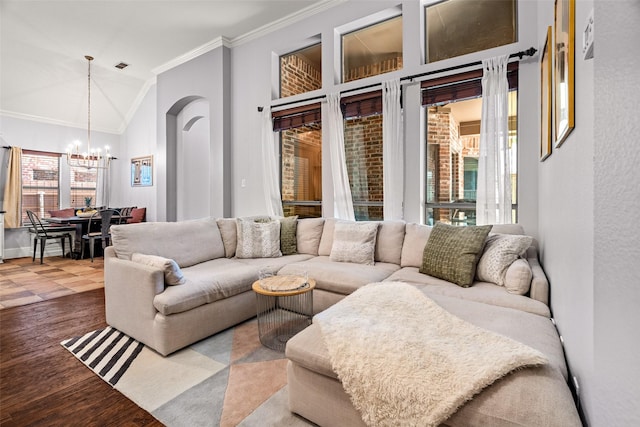 living room featuring a healthy amount of sunlight, wood finished floors, a notable chandelier, and crown molding