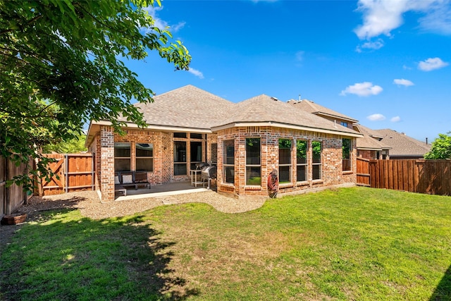 back of property with a shingled roof, a patio area, a fenced backyard, and brick siding