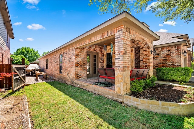 back of house featuring a lawn, brick siding, fence, and a patio area