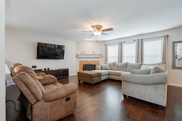 living area featuring a tile fireplace, a ceiling fan, baseboards, and dark wood finished floors