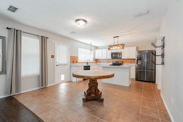 kitchen with light countertops, visible vents, stainless steel appliances, and decorative backsplash