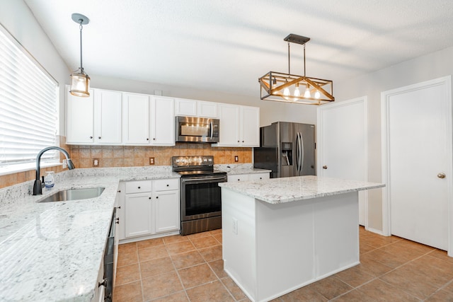 kitchen featuring appliances with stainless steel finishes, white cabinetry, a kitchen island, and a sink