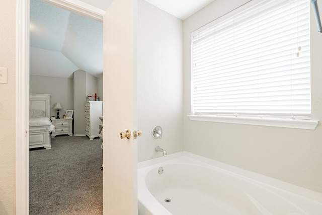 full bathroom with a healthy amount of sunlight, a bath, and vaulted ceiling