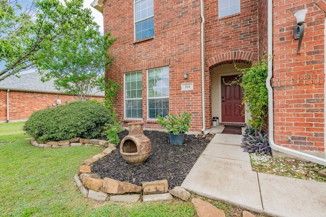 doorway to property with a yard and brick siding