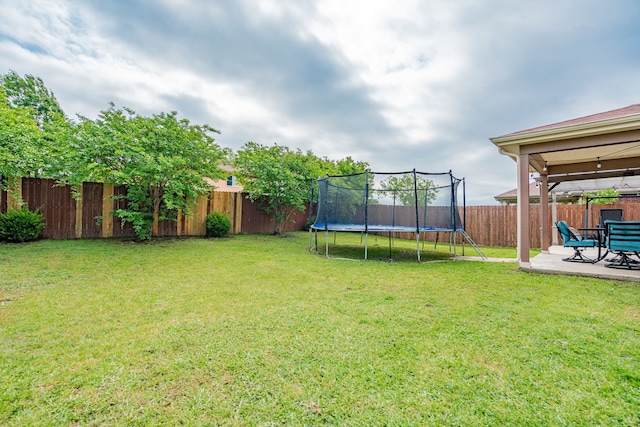 view of yard with a trampoline, a fenced backyard, and a patio area