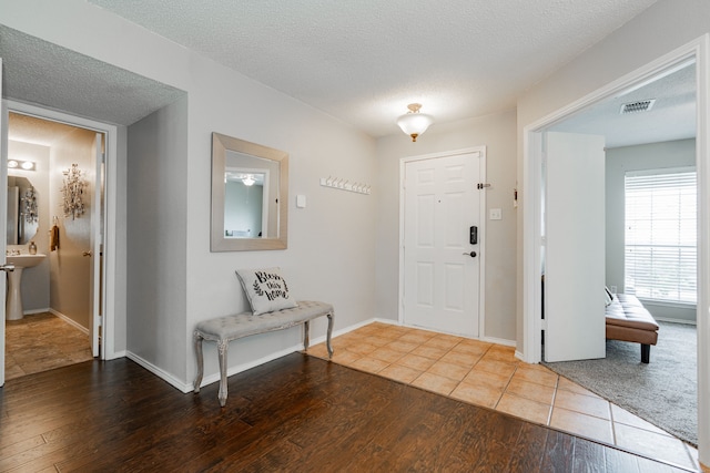 entryway with wood finished floors, visible vents, baseboards, and a textured ceiling