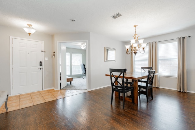 dining space featuring a chandelier, visible vents, wood finished floors, and baseboards