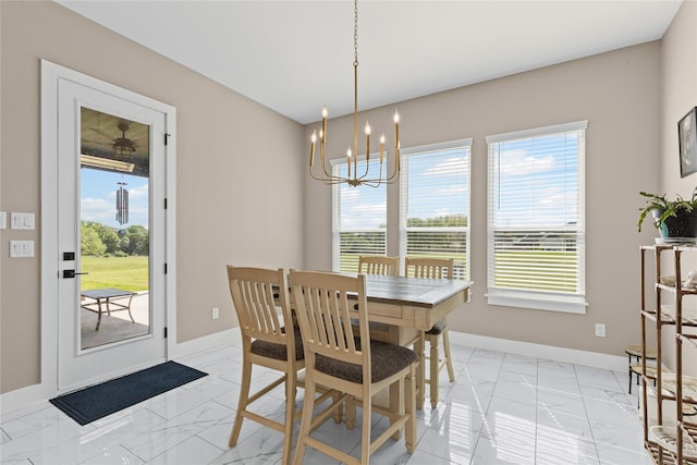 dining space featuring an inviting chandelier, marble finish floor, and baseboards