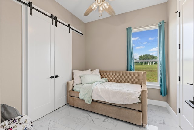 bedroom with a barn door, a ceiling fan, marble finish floor, and baseboards