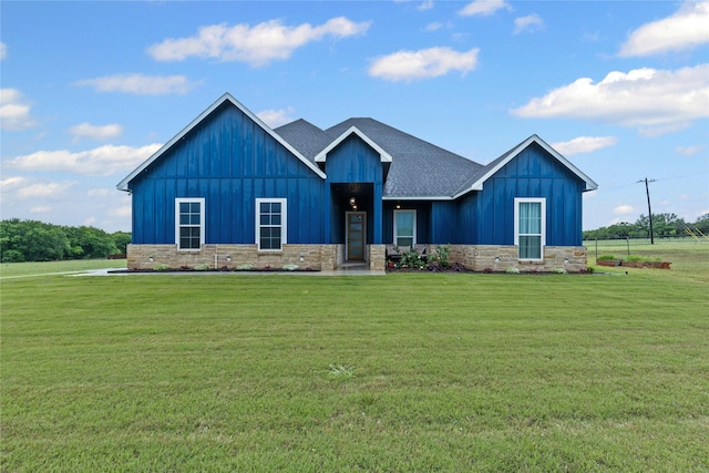 view of front of property with board and batten siding, a front lawn, and roof with shingles