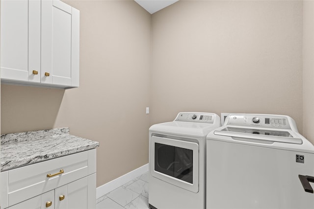 clothes washing area with independent washer and dryer, cabinet space, marble finish floor, and baseboards