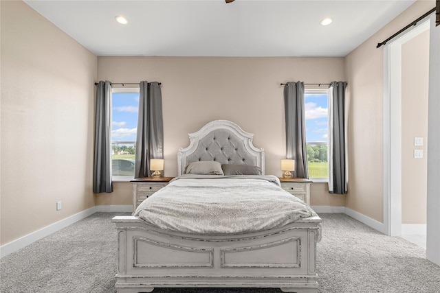 bedroom featuring baseboards, light carpet, and multiple windows