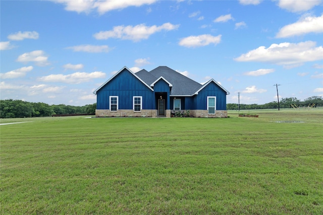 view of front of property featuring board and batten siding, a front lawn, and stone siding