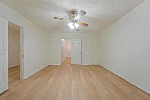 spare room featuring a ceiling fan, light wood-type flooring, a textured ceiling, and visible vents