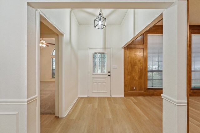 foyer with ornamental molding and light wood-style flooring