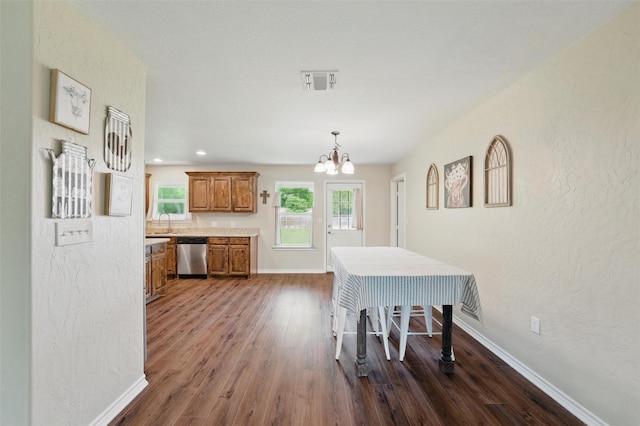 dining room featuring dark wood-style floors, a chandelier, and a textured wall