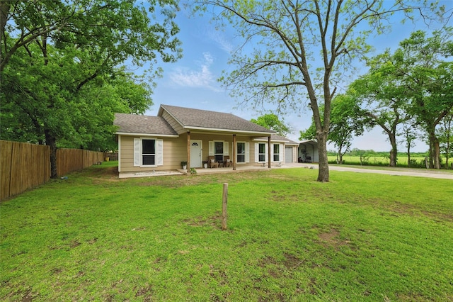 back of property with concrete driveway, fence, and a yard