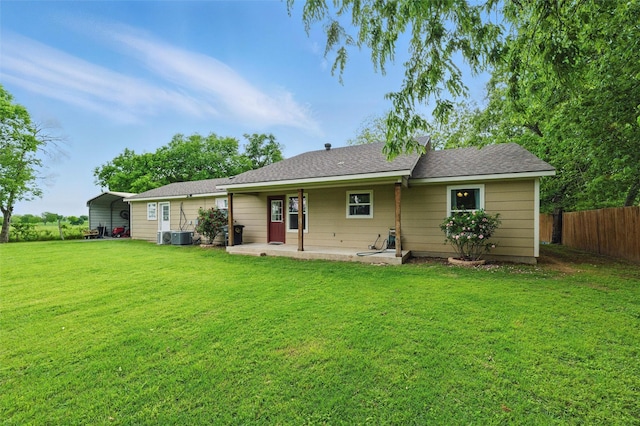 rear view of property featuring a patio, fence, a detached carport, and a lawn